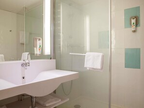 A bathroom with a white sink, a glass shower enclosure, and a towel rack.
