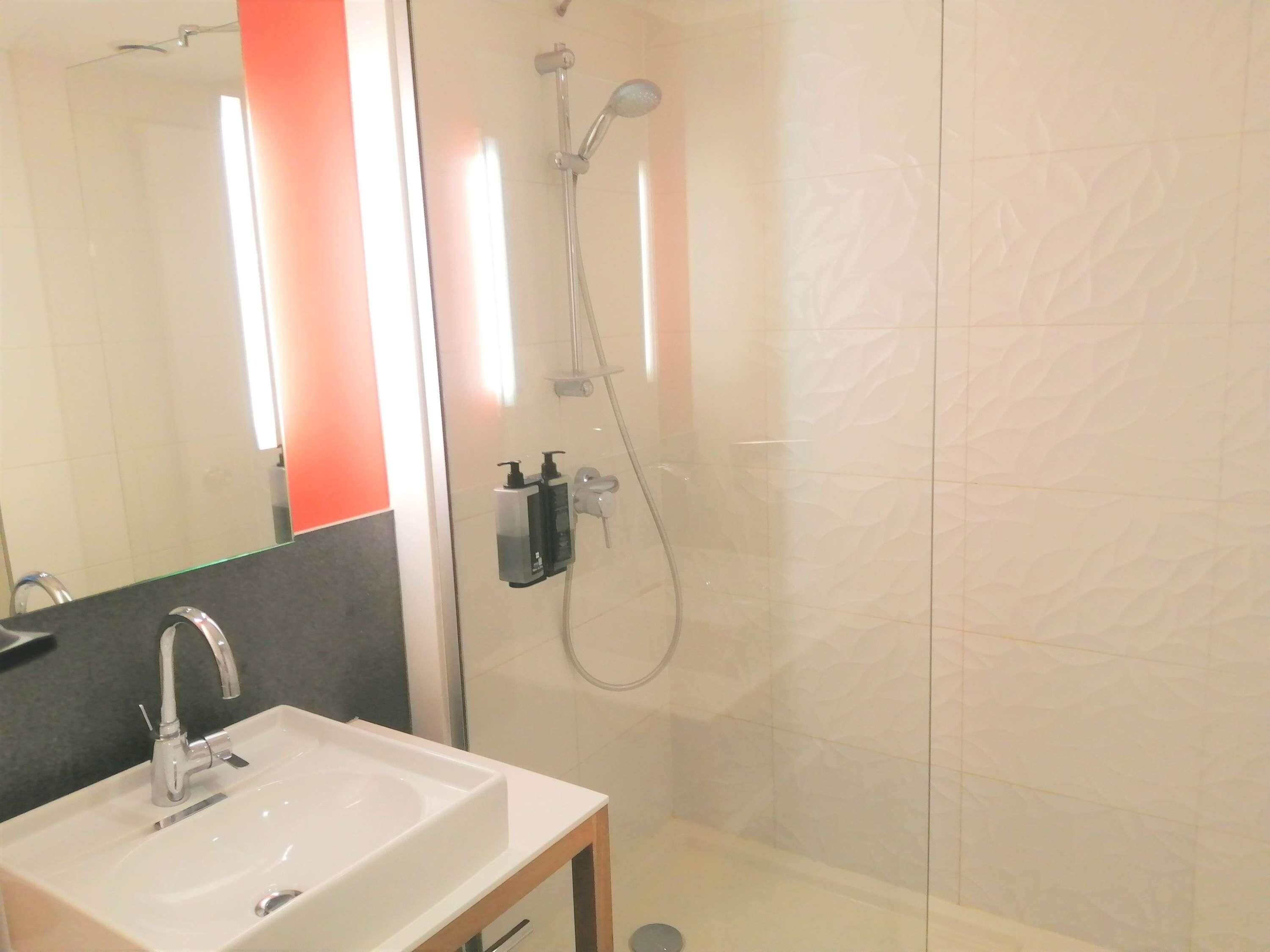 A bathroom with a sink, mirror, and shower.