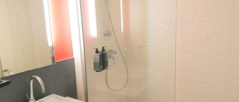 A bathroom with a sink, mirror, and shower.