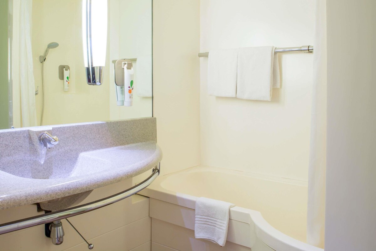Un baño con lavamanos, espejo, ducha e inodoro.