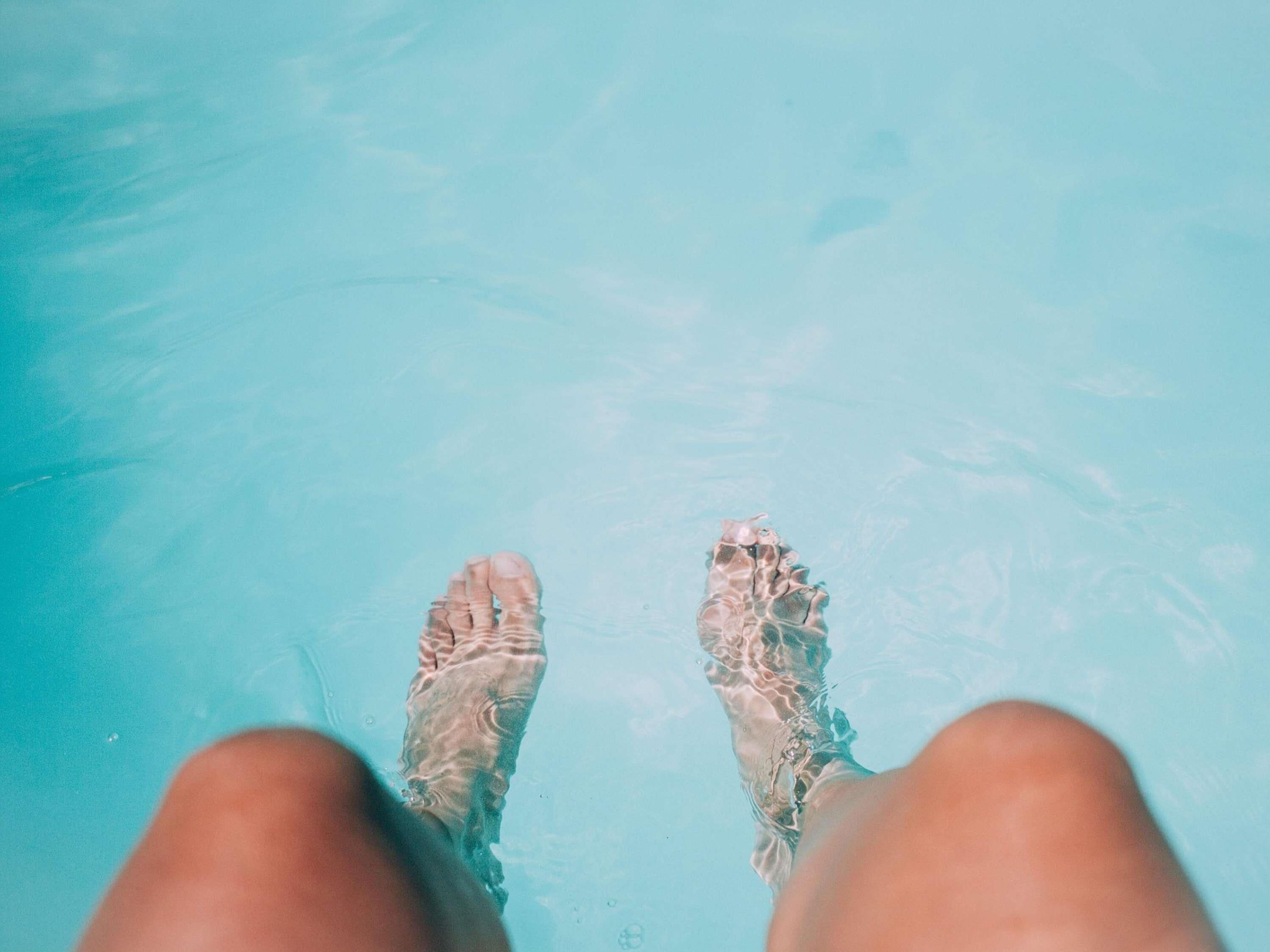 A pair of feet in a clear blue pool.