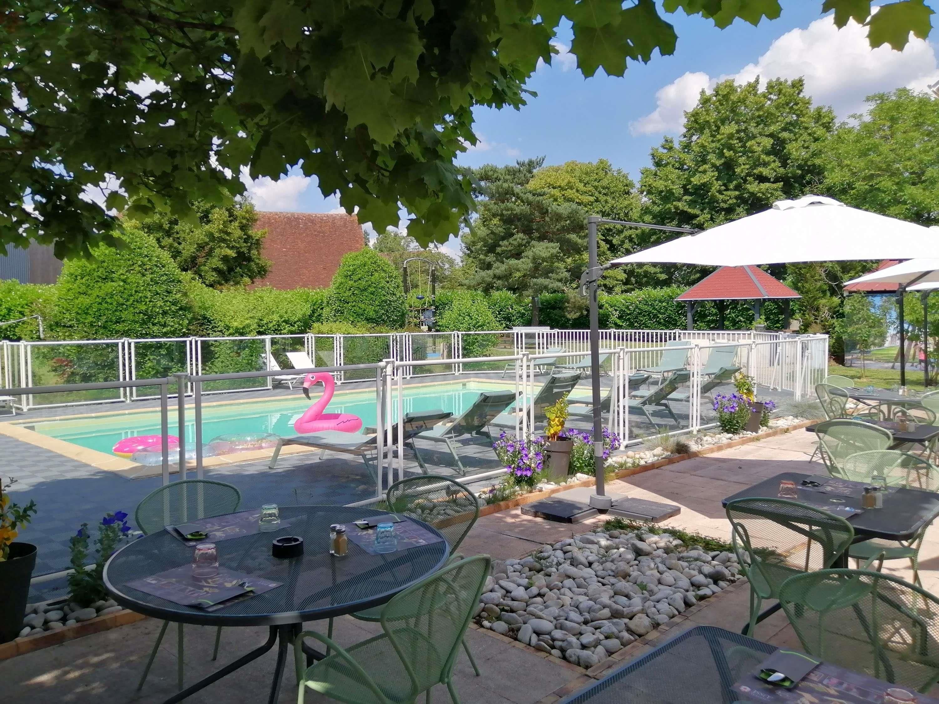 Un área de piscina al aire libre con sillones de descanso, una decoración de flamenco y mesas con sillas.