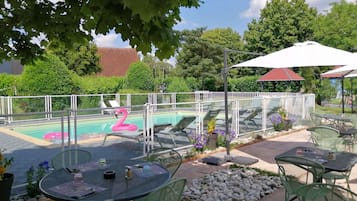 Un área de piscina al aire libre con sillones de descanso, una decoración de flamenco y mesas con sillas.