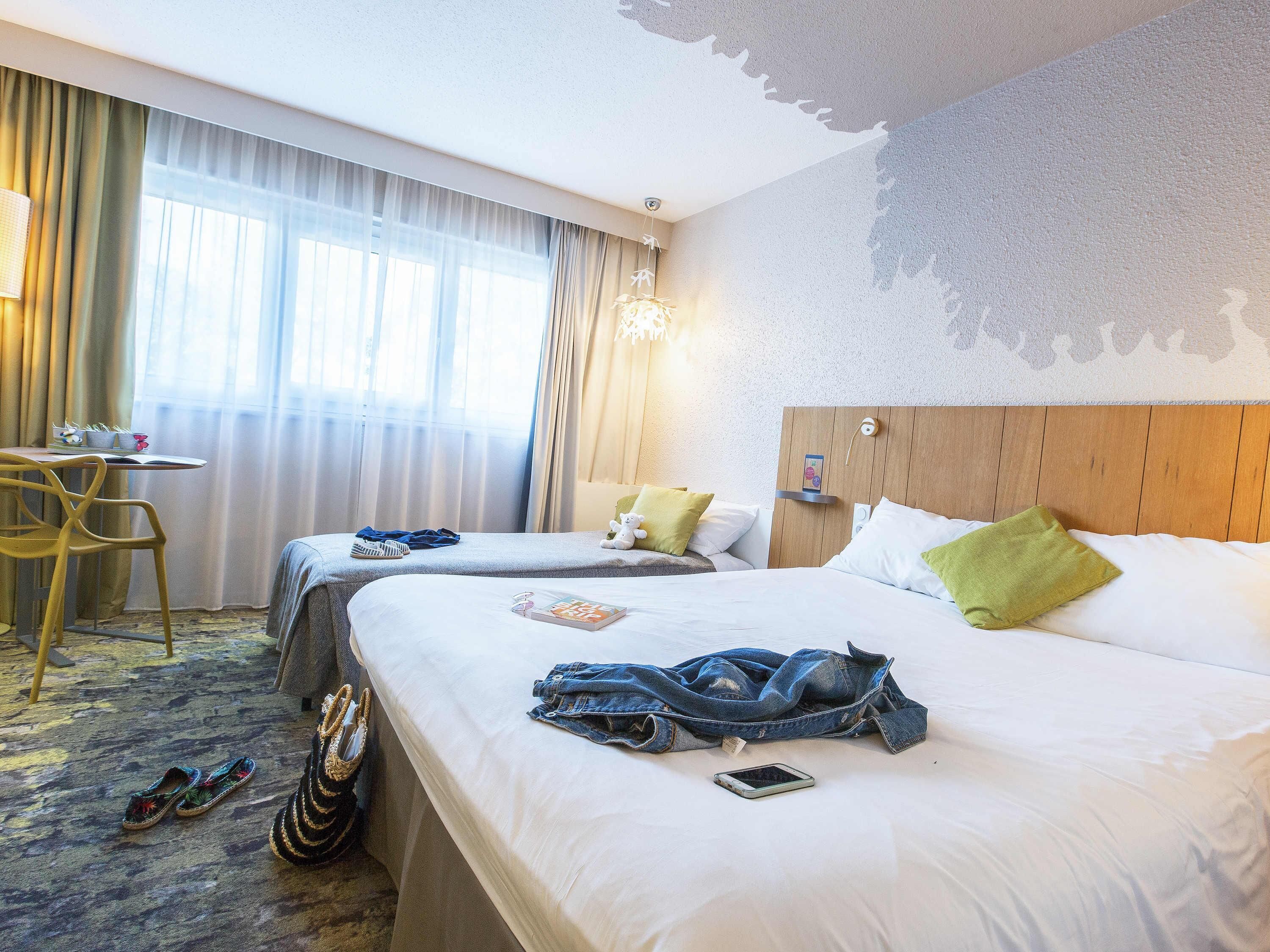A hotel room with two beds, a desk, and a chair.