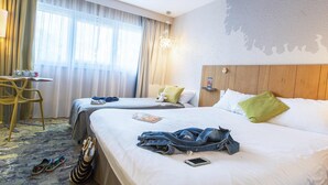 Habitación de hotel con dos camas, un escritorio y una silla.