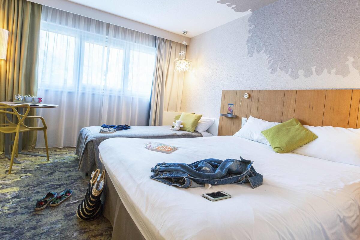 Une chambre d’hôtel avec deux lits, un bureau et une chaise.