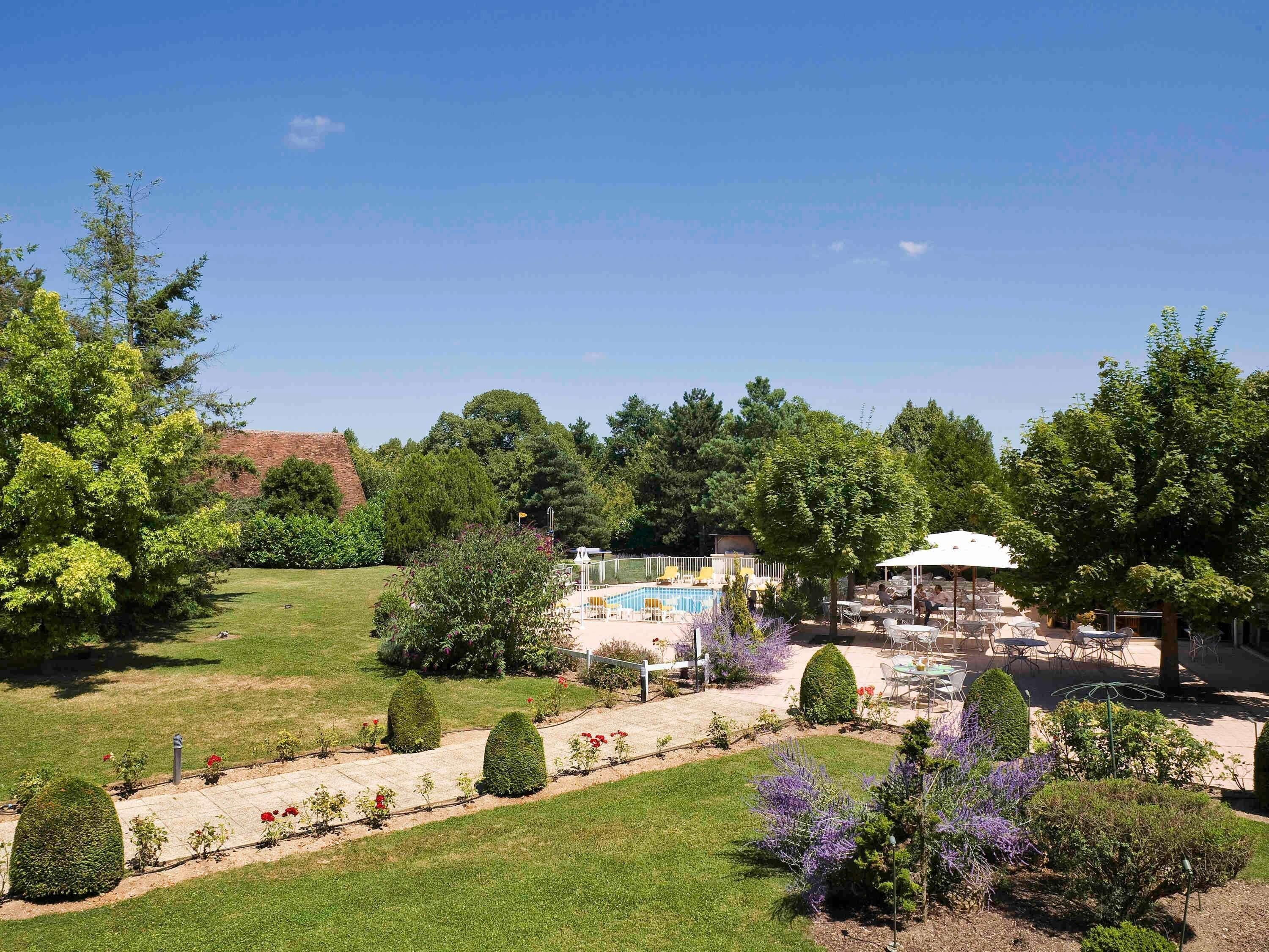 A landscaped garden with a pool, outdoor seating, and a gazebo.