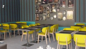 Un restaurant avec des chaises et des tables jaunes, un papier peint à rayures et des tableaux encadrés accrochés au mur.