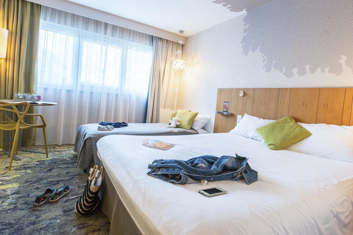 A hotel room with two beds, a desk, and a chair.