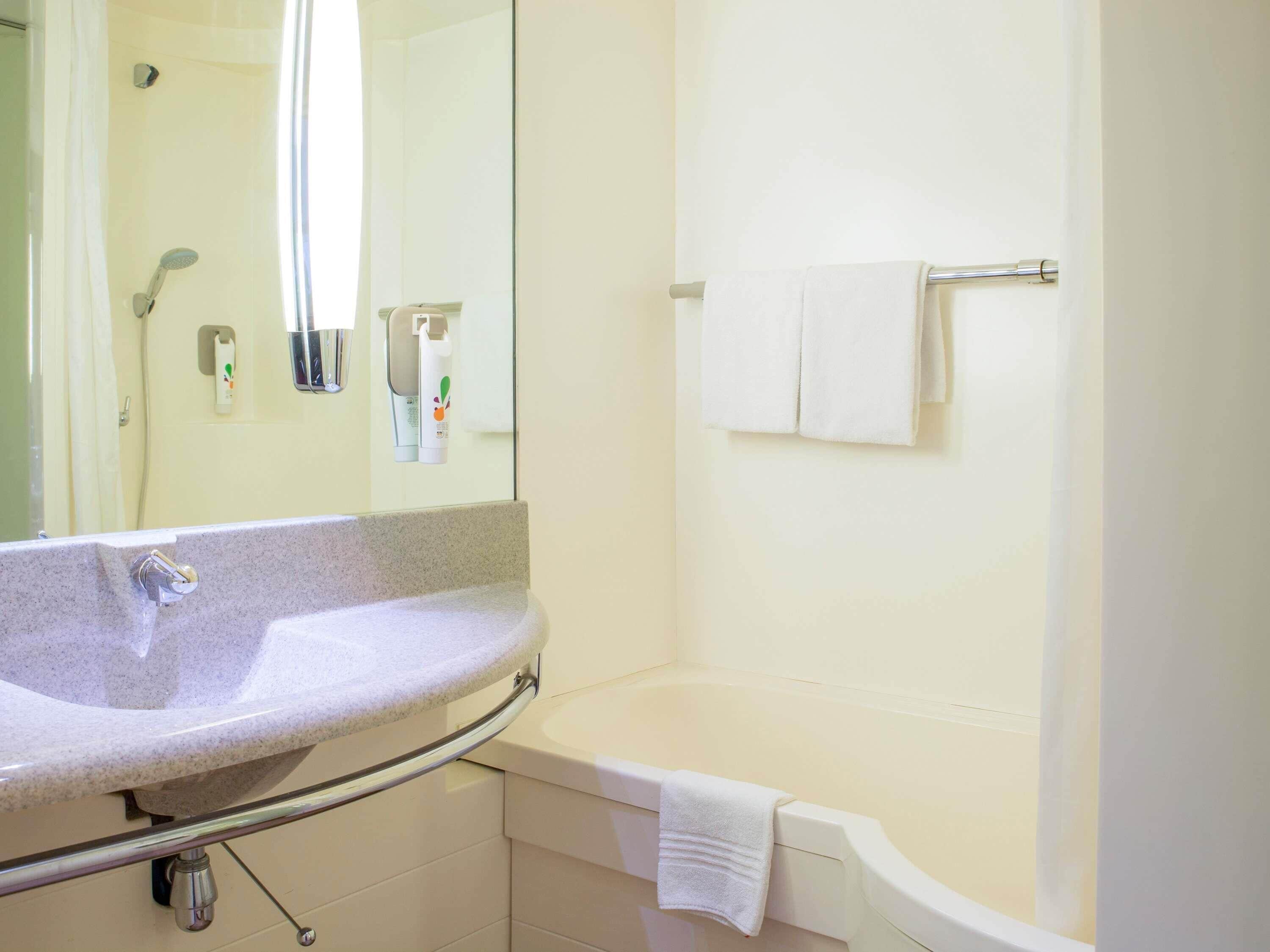 Een badkamer met een wastafel, spiegel, douche en toilet.