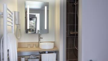 A modern bathroom with a white sink, mirror, and towel rack.