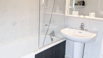 A modern bathroom with a glass-enclosed shower, a white sink, and a mirror with built-in lighting.