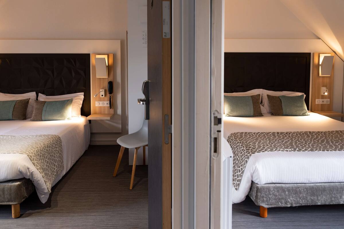 A hotel room with two beds, a desk, and a chair.