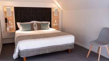 A neatly made bed with a patterned bedspread, two pillows, and a bedside table with a lamp.