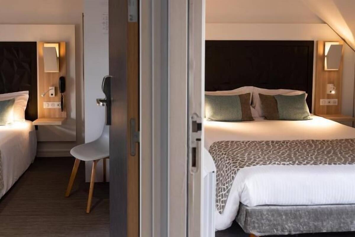 A hotel room with two beds, a desk, and a chair.