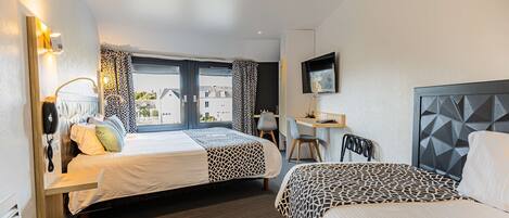 Une chambre d’hôtel avec deux lits, un bureau, une chaise et un téléviseur.