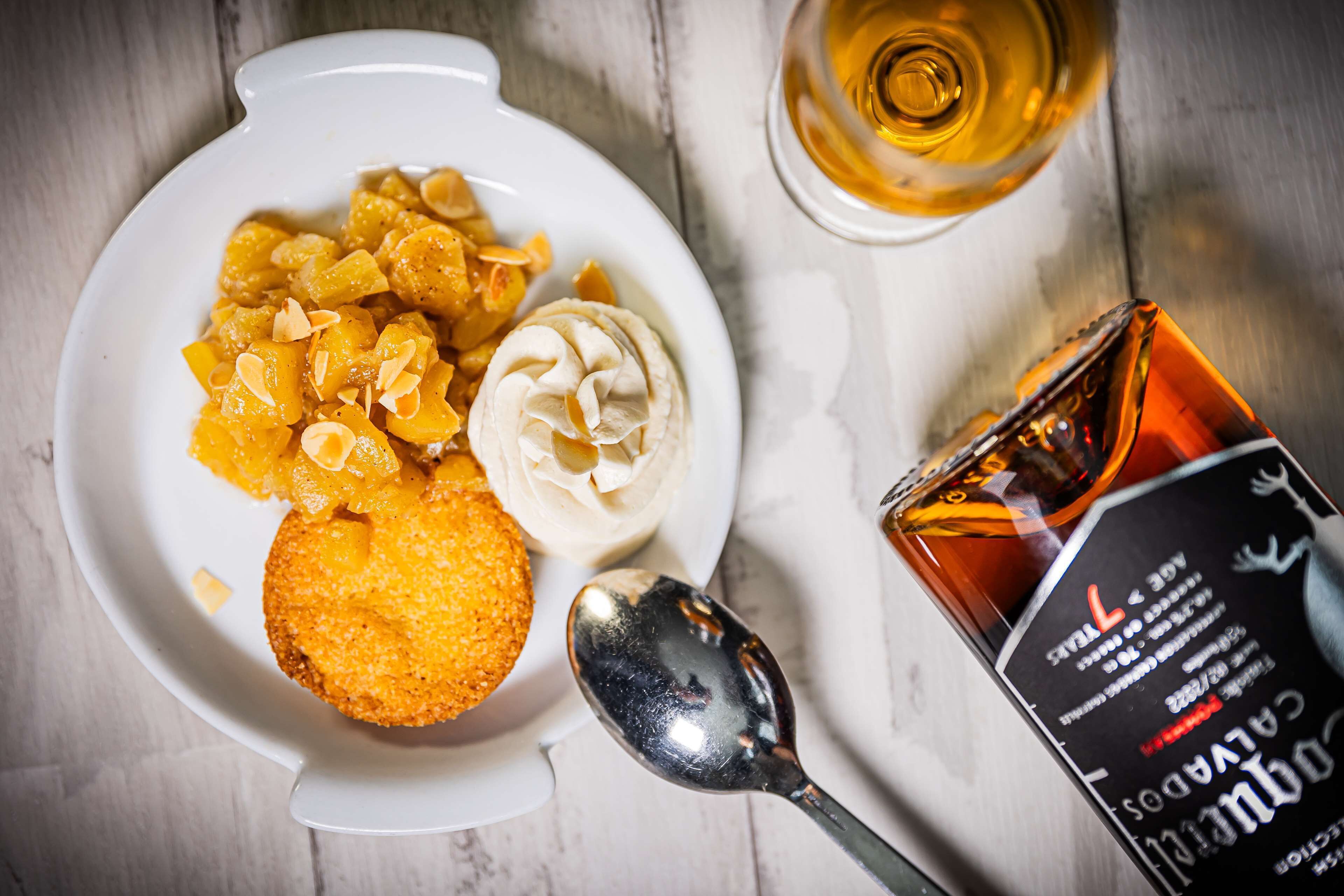 A plate with food and a bottle of liquor on a wooden surface.