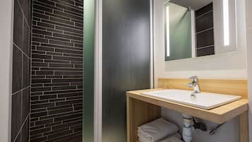 Une salle de bain moderne avec un mur en briques sombres, un meuble-lavabo en bois avec un évier blanc et un miroir au-dessus.
