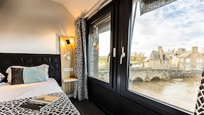 A hotel room with a large window overlooking a river and historic buildings. - Best Western Le Moulin De Ducey (Ducey-les-Chéris)