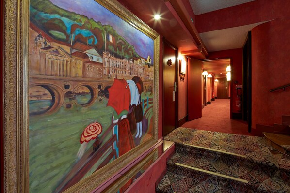 A hallway with a large mural, carpeted stairs, and a fire extinguisher.