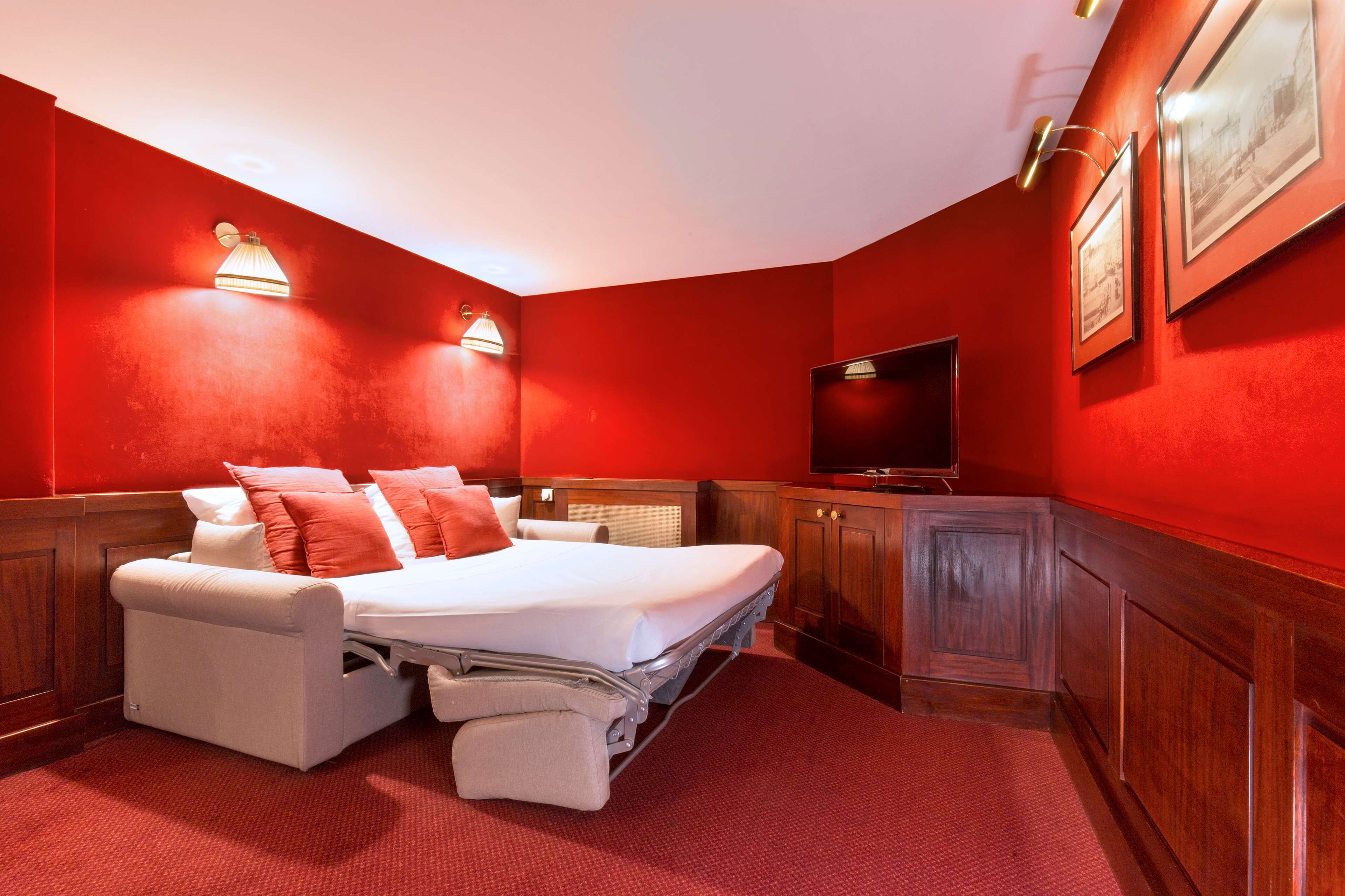 A hotel room with a bed, a TV, and wooden paneling.