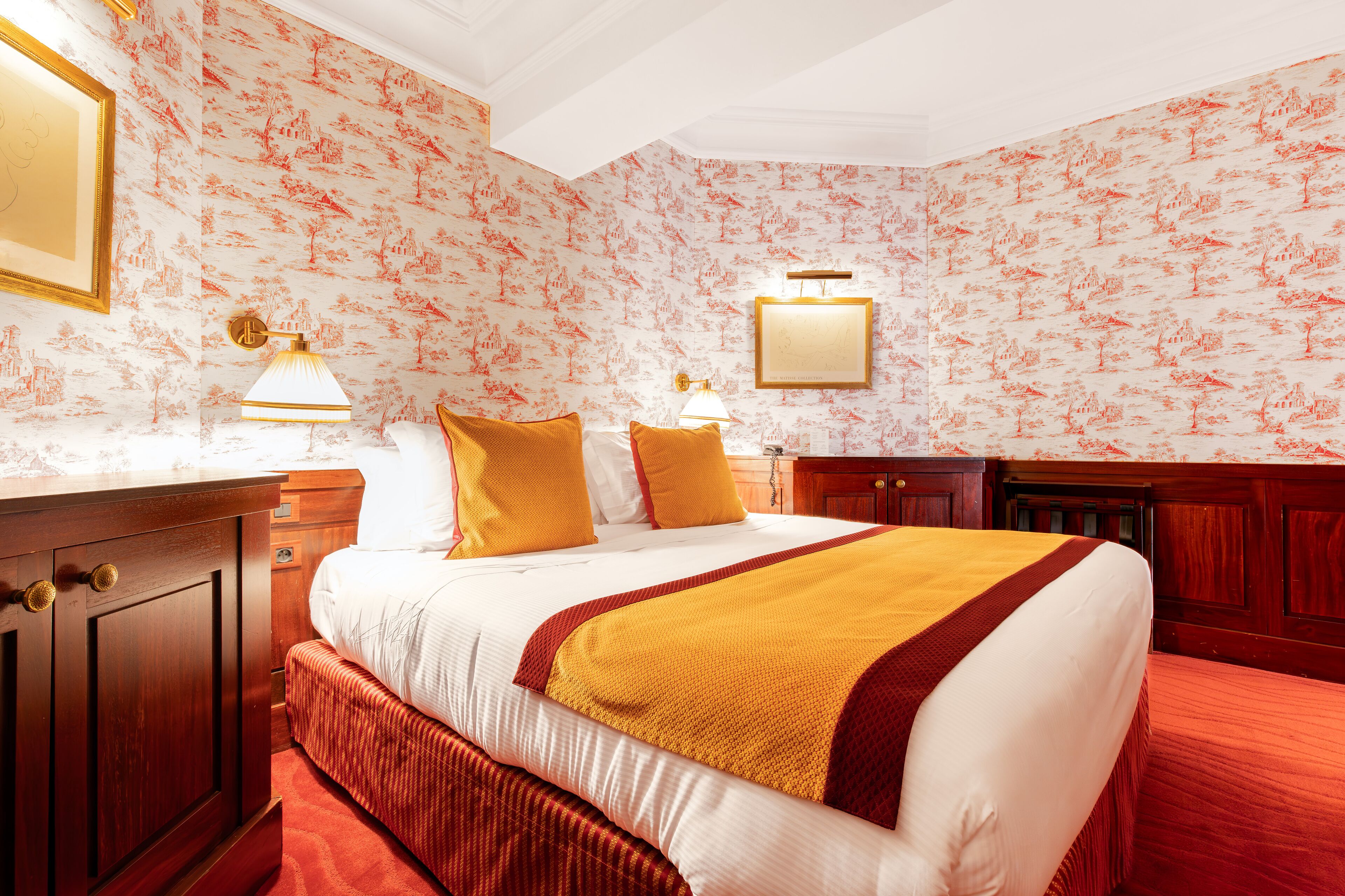 Una habitación de hotel con una cama grande, dos mesitas de noche, un armario y un espejo.