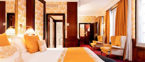 Une chambre d’hôtel dotée d’un grand lit, d’un coin salon avec des fauteuils et offrant une vue sur la ville.