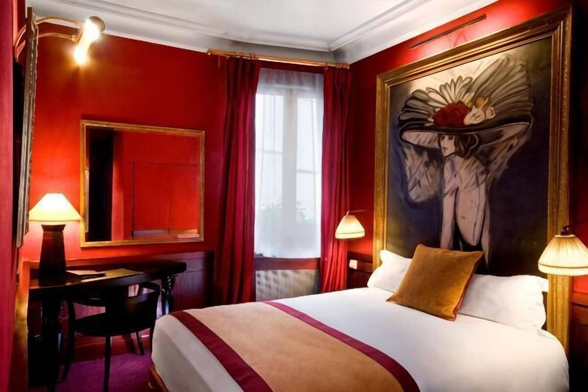 Una habitación de hotel con una cama grande, un escritorio, una silla y un cuadro en la pared.