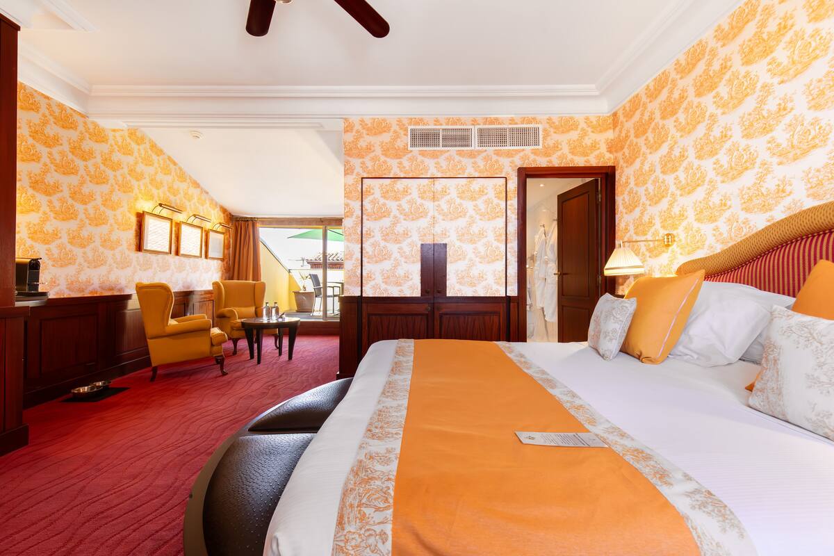 Una habitación de hotel con una cama grande, un escritorio con silla, una mesita y un sofá.