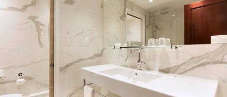 A modern bathroom with a marble sink, a glass shower enclosure, and a large mirror.