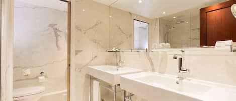 A modern bathroom with two sinks, a toilet, and a shower.