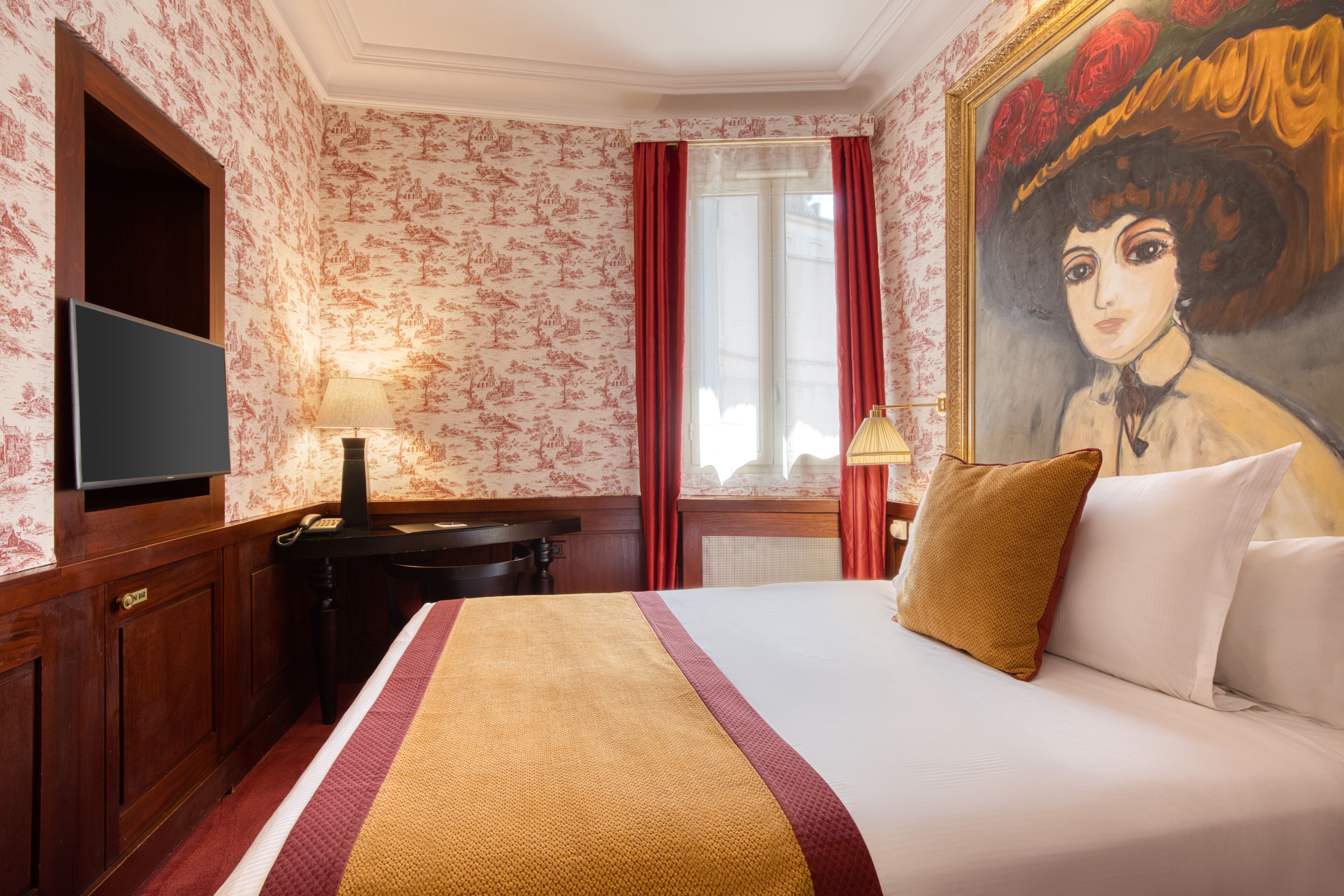 A hotel room with a large bed, a television, a desk with a lamp, and a painting on the wall.
