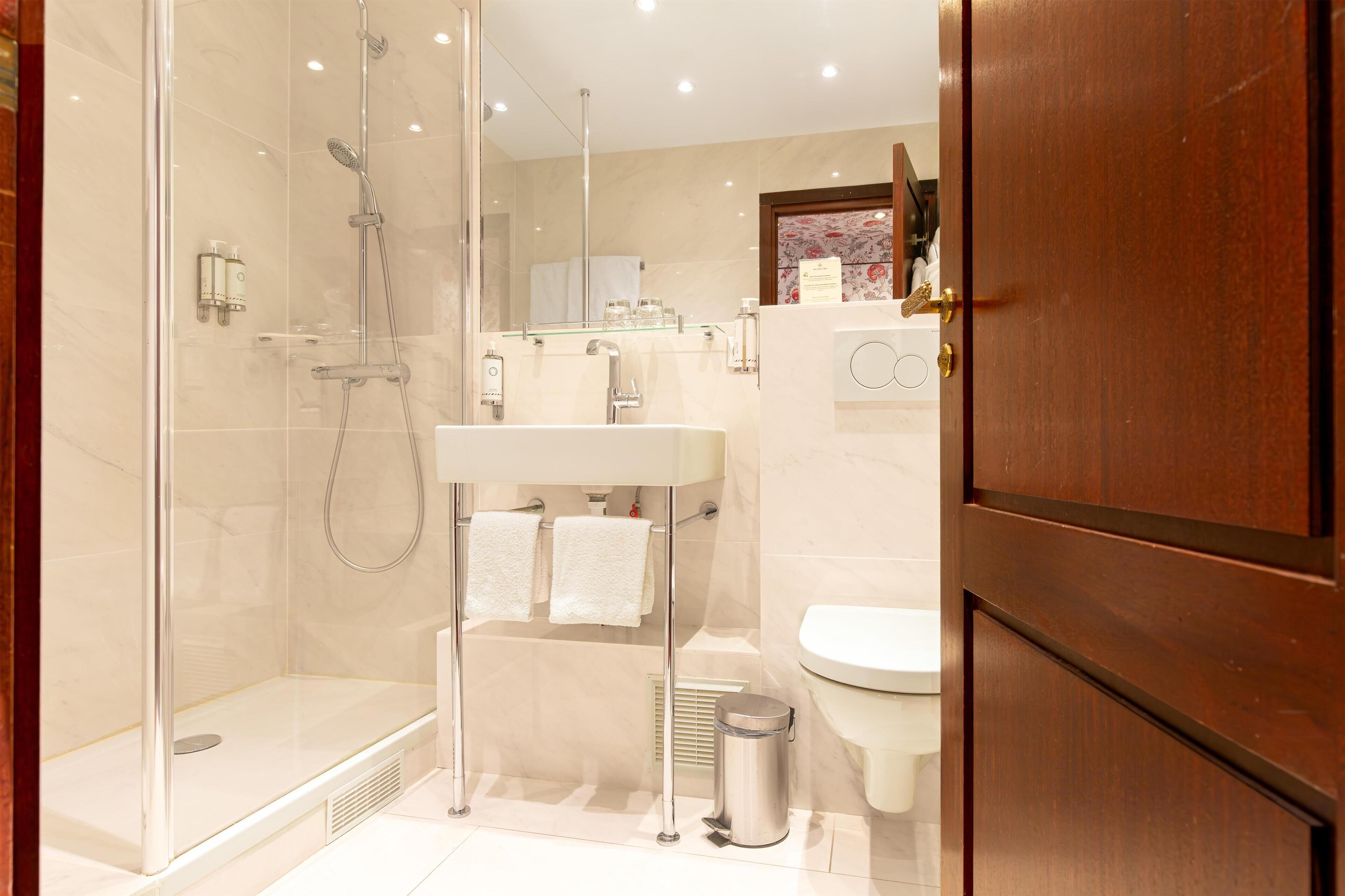 Un baño moderno con ducha de vidrio, un lavamanos blanco y un inodoro.