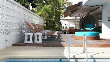 Un espace aménagé au bord de la piscine, avec des chaises longues, un jacuzzi et une terrasse en bois.