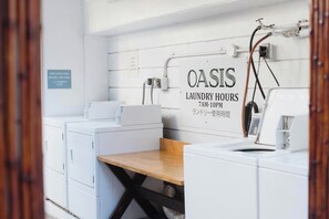 A laundry facility with a sign indicating 'OASIS LAUNDRY HOURS 7AM-10PM'. - Oasis Hotel Waikiki (Honolulu)