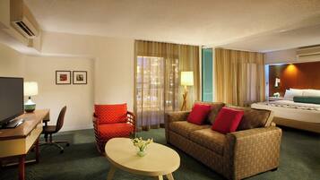 Una habitación de hotel con cama, sofá, escritorio y silla, y televisor.