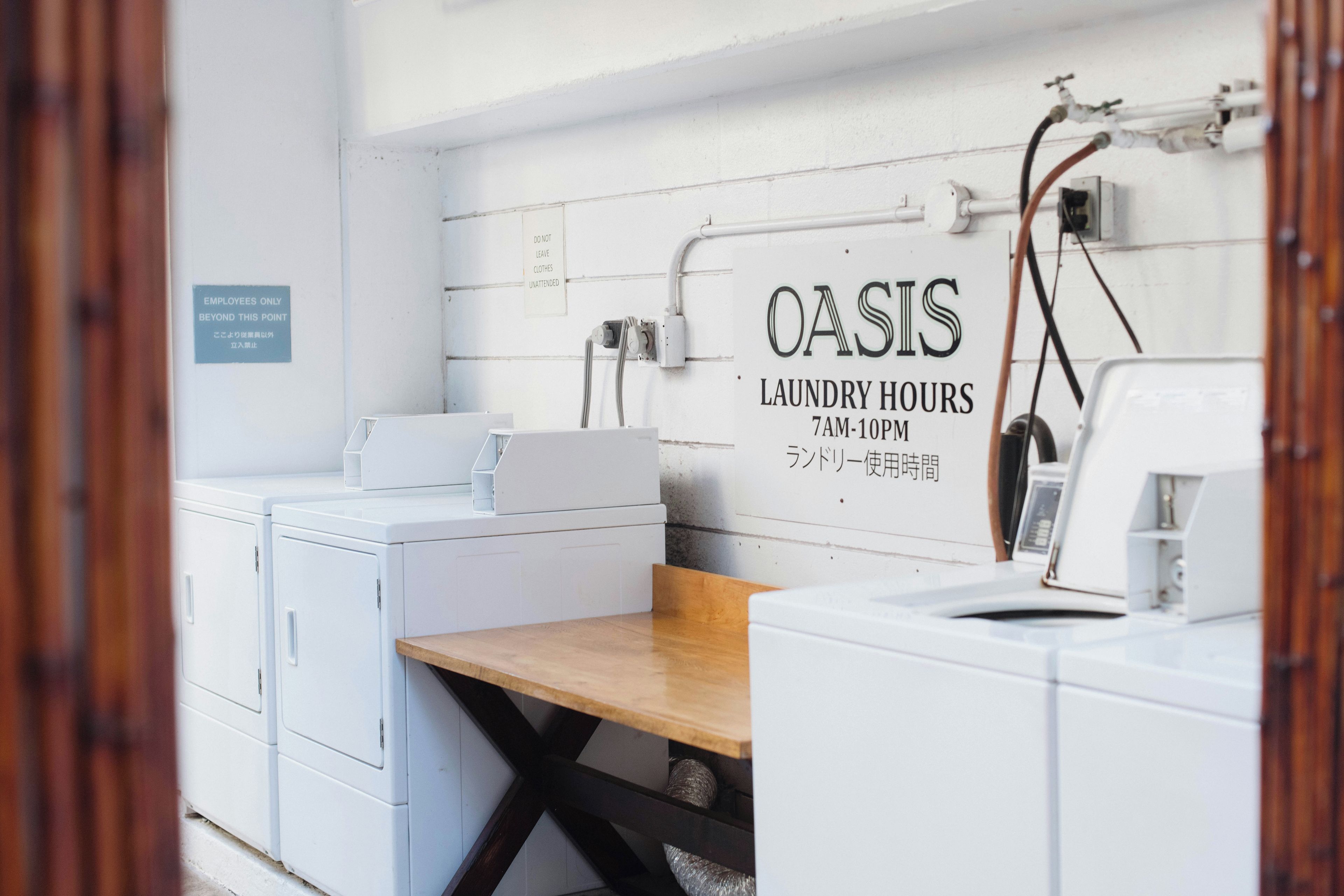 A laundry facility with a sign indicating 'OASIS LAUNDRY HOURS 7AM-10PM'.