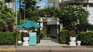 Entrada de hotel con un letrero, un camino y abundante vegetación.