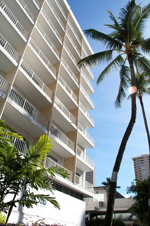 A multi-story hotel with balconies, palm trees, and a clear sky. - Oasis Hotel Waikiki (Honolulu)