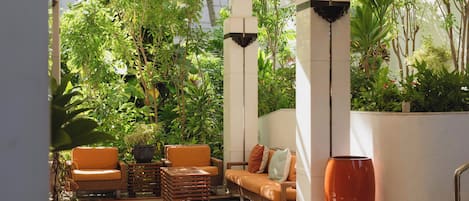 Un jardín interior con asientos, un jarrón grande y un ventilador de techo.