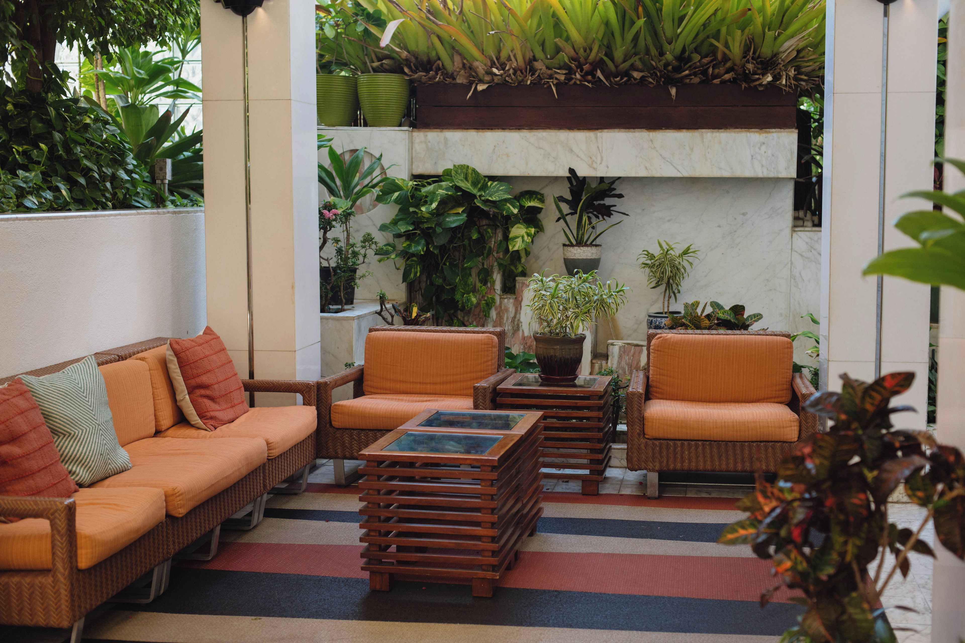A cozy outdoor seating area with wicker furniture and a variety of potted plants.