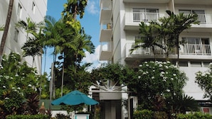 A multi-story hotel with balconies and a palm tree in front.