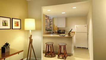 A compact kitchen with a refrigerator, microwave, and a small dining area with stools.