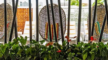A room with a large window, a wicker chair, and a plant.