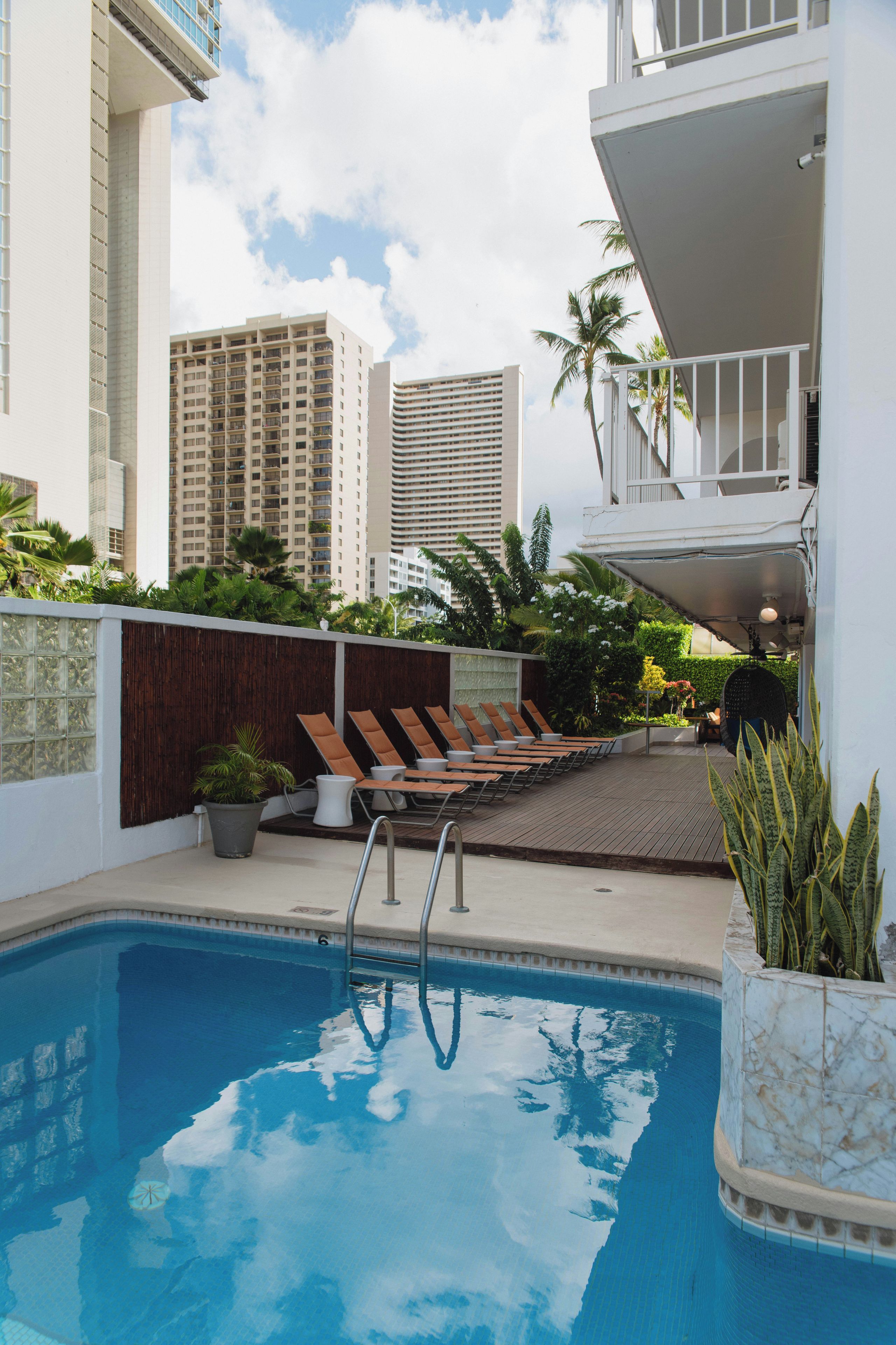 A swimming pool with lounge chairs and a view of tall buildings in the background.