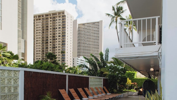 A swimming pool with lounge chairs and a view of tall buildings in the background.