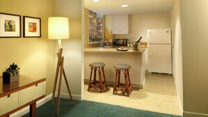 A compact kitchen with a refrigerator, microwave, and a small dining area with stools.