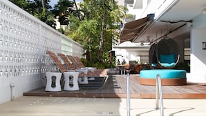 A poolside area with a pool, lounge chairs, and a hot tub.