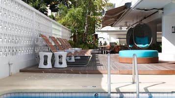 Una piscina al aire libre, sillones reclinables de piscina