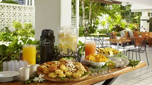 Un bufé de desayuno con diversos pasteles, un frutero y una estación para bebidas.